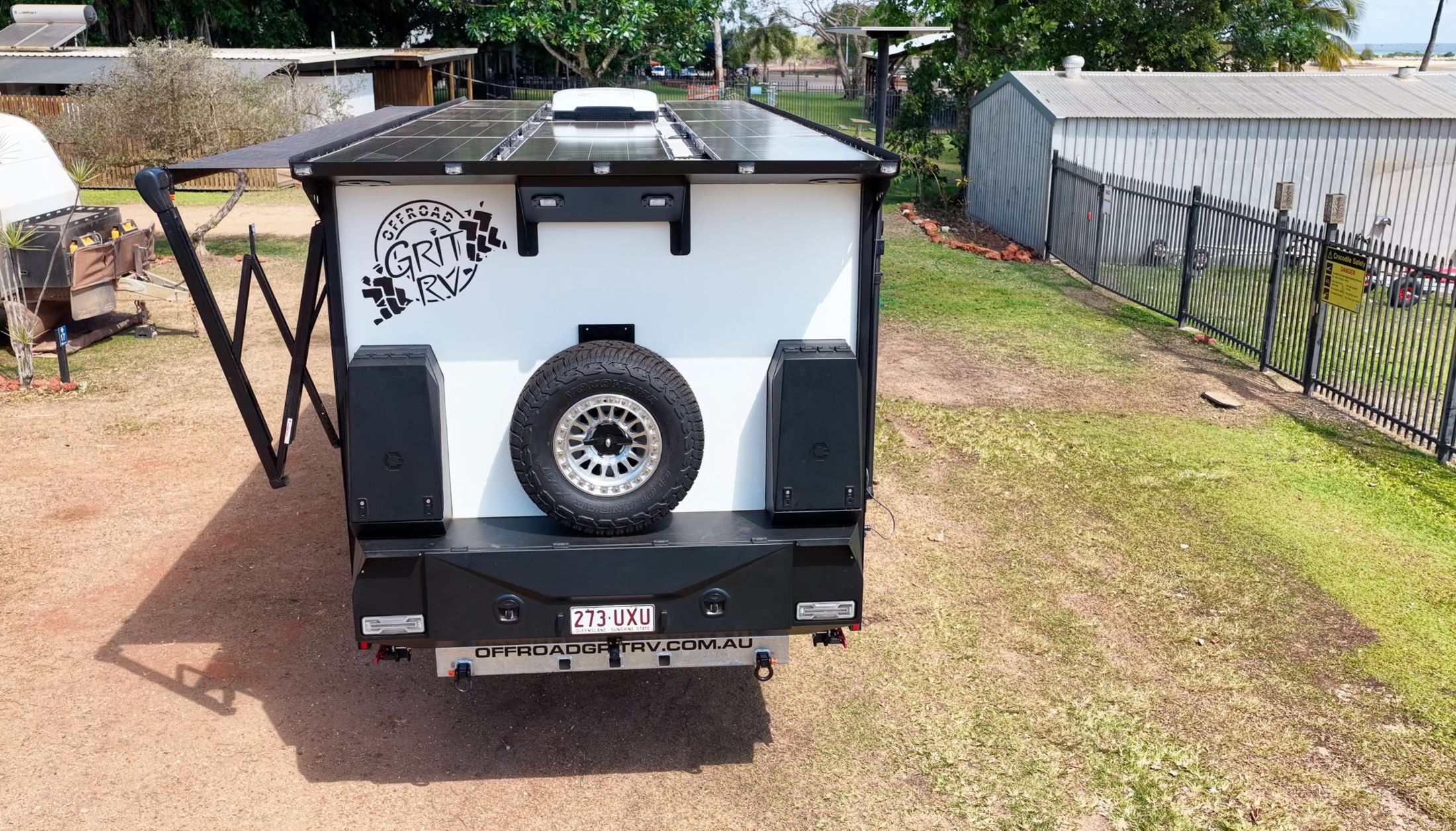 Rear of an Offroad Grit RV composite van: white body, black storage boxes and spare wheel
