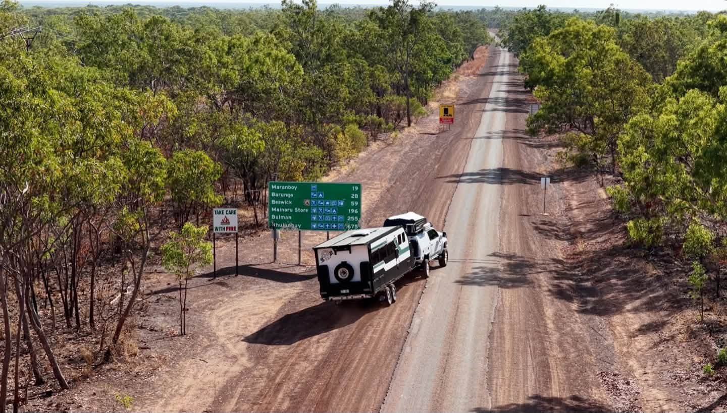 ADU's van and ute pulled up at a road sign in the Northern Territory, from the air