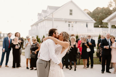 Bride and groom kiss as wedding guests applaud. Photo by Brittany Lauren
