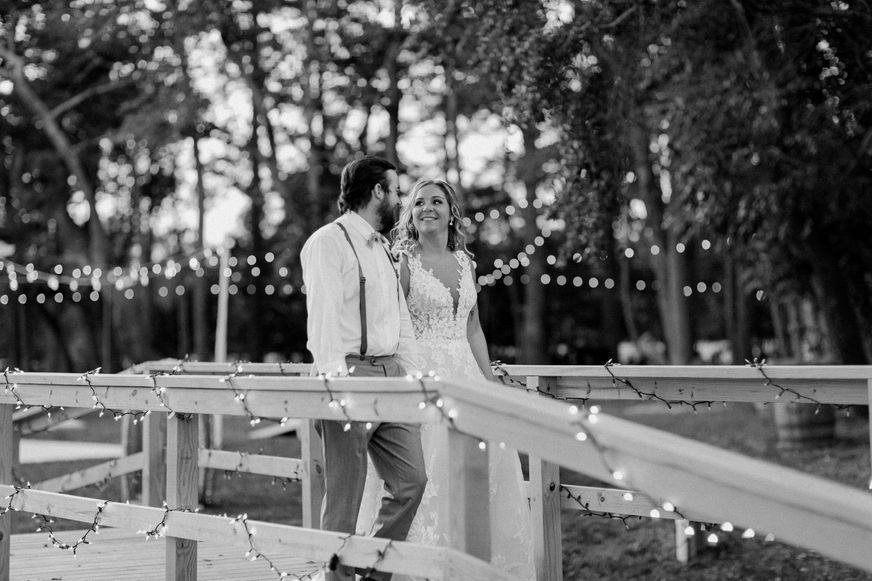Black and white portait of bride and groom crossing scenic bridge at outdoor wedding venue. Photo by Brittany Lauren