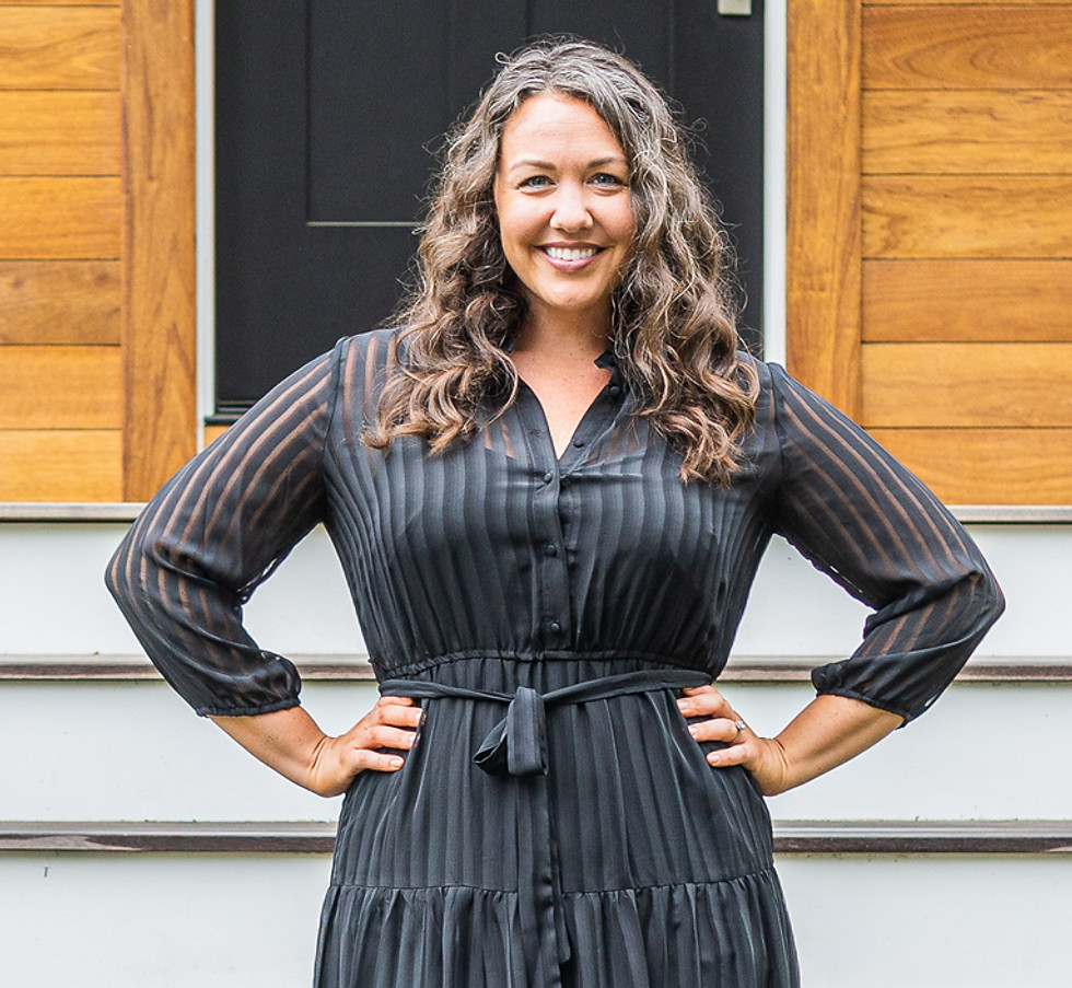 A woman elegantly stands on steps wearing a black dress, exuding grace and poise in her attire. A team realtor.