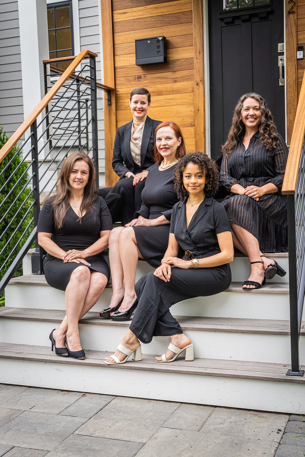 Photo of The Prosperity Group team members sitting together on stairs of modern home