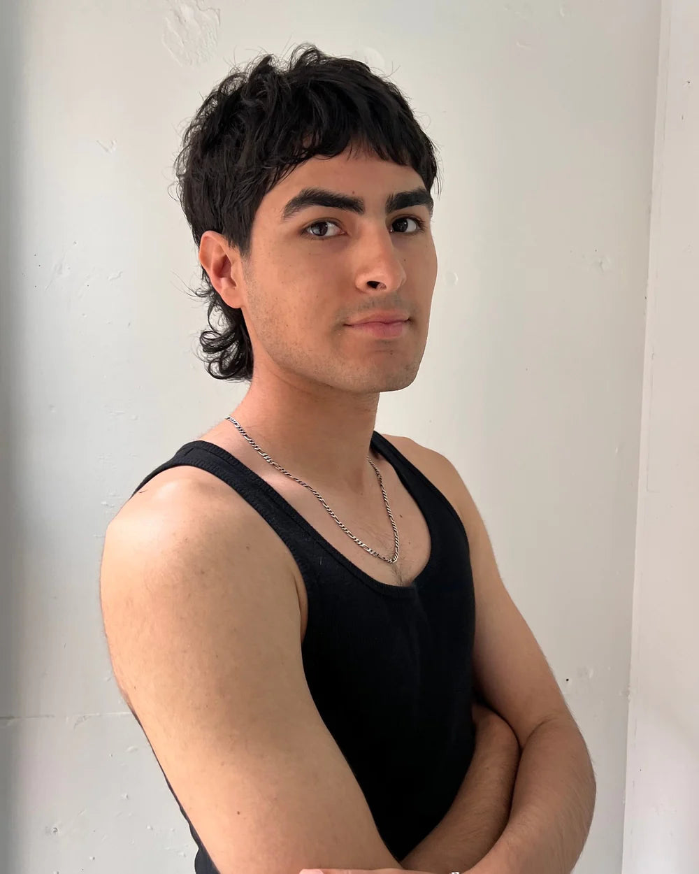 Man posing with arms crossed against white background