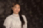 Smiling Yzah Calunsod in a white lace blouse posed against a dark blurred studio backdrop, looking calm and friendly.
