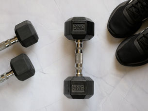 Some dumbbells and running shoes on a white floor