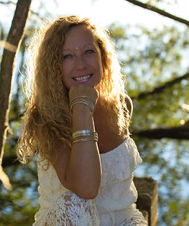 This is YASMINA the owner of Happy Healthy Life, she is sitting in front of a tree smiling, her chin is resting on her han