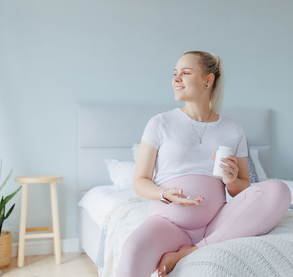 Smiling young pregnant woman taking white round pill, daily vitamins for hair and skin, he
