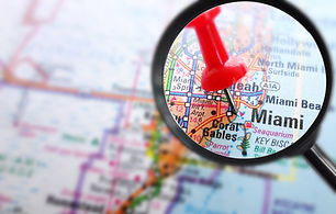 Closeup of Miami map with red push pin and magnifying glass .jp