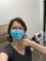 Annie with short hair and a mask in a medical building