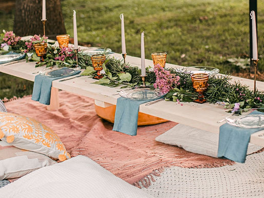 backyard outdoor soirée floral table setting with throw pillows in pastel