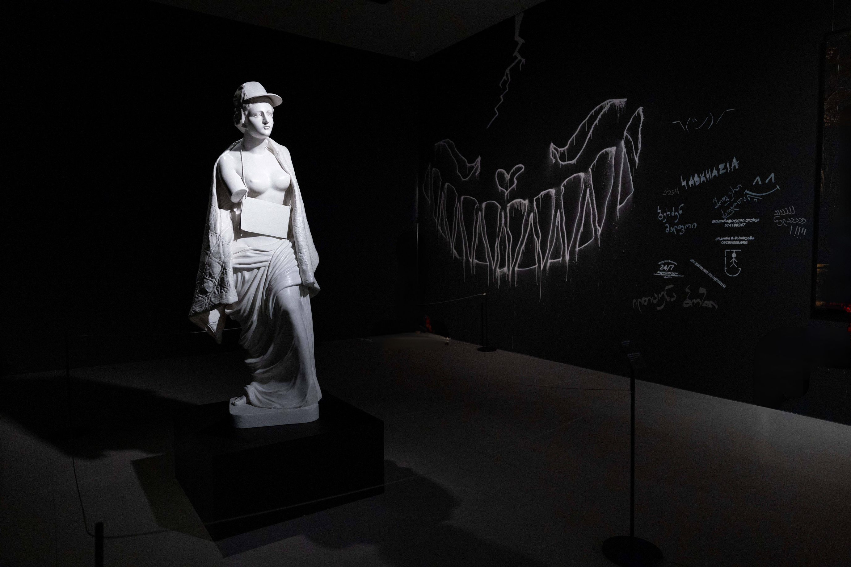Dramatically lit artwork inside the Banksy exhibition.