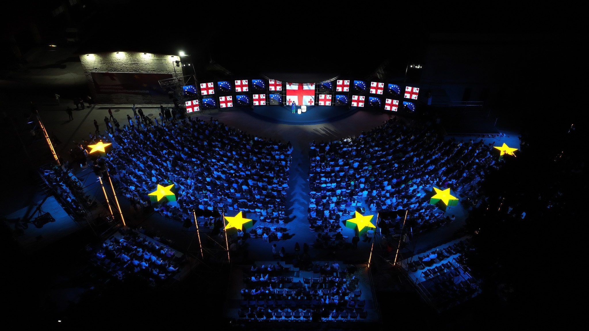 Outdoor event framed by illuminated European stars.