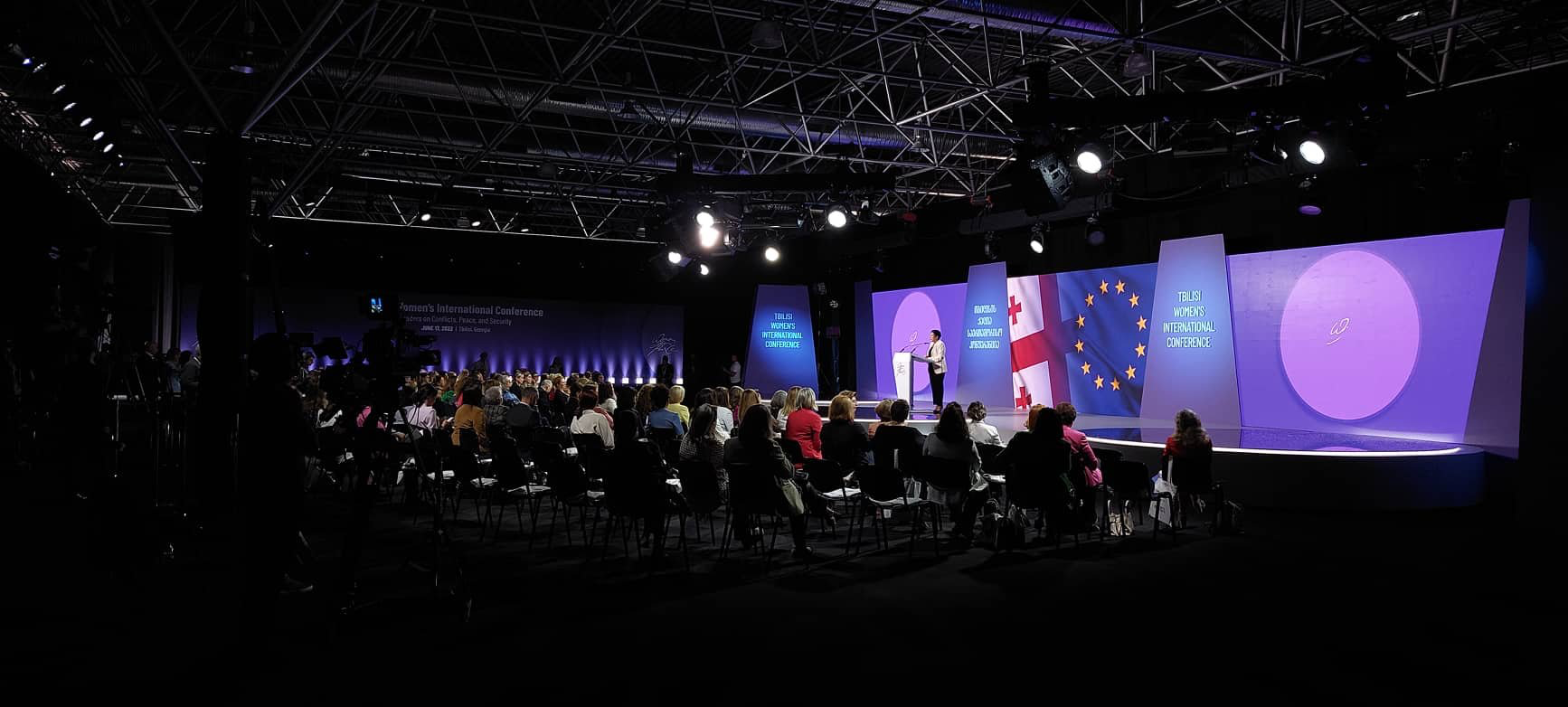 Conference audience and a wide presentation screen.