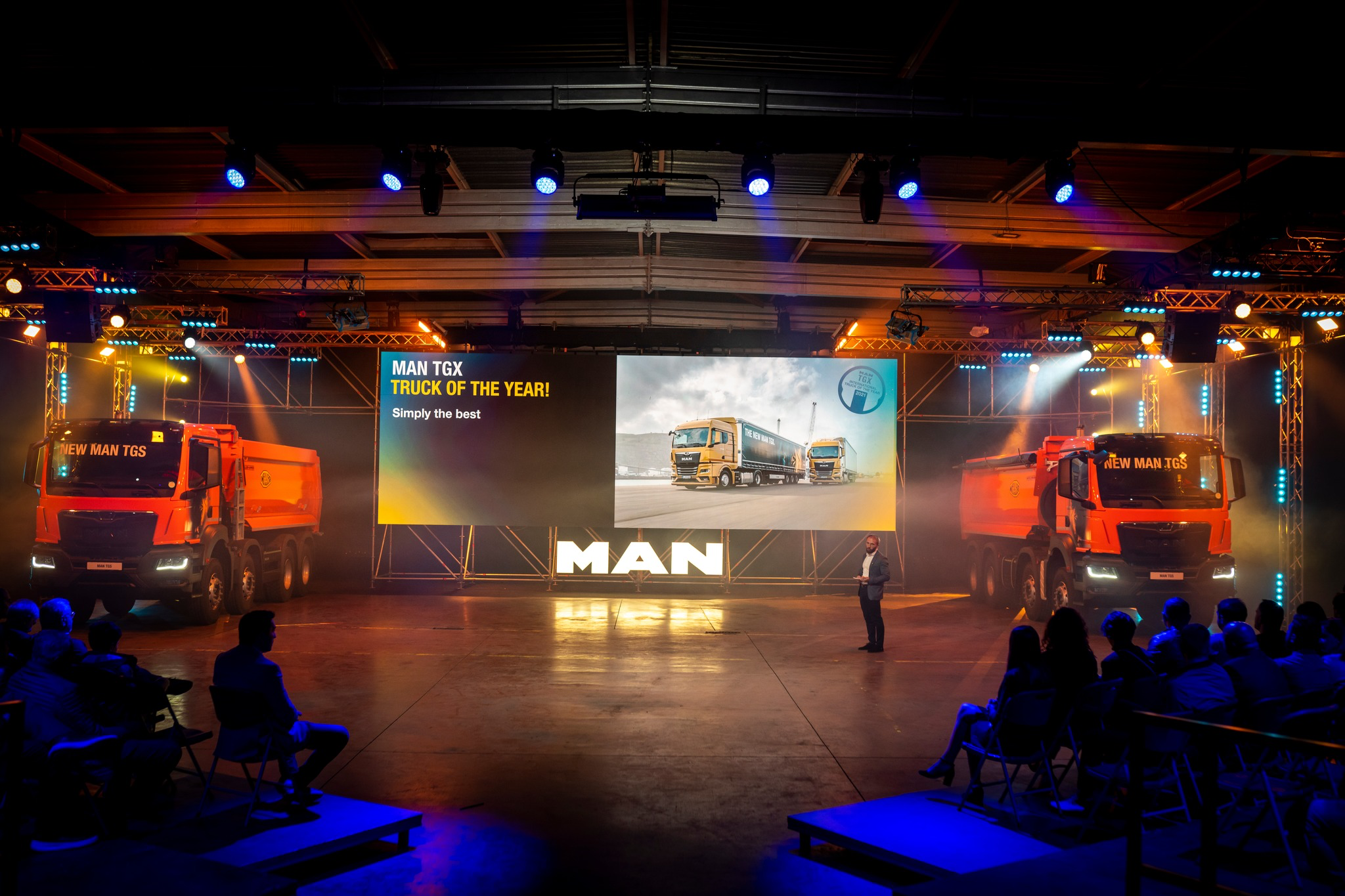 MAN trucks on the launch stage, framed by screens and lighting.