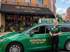 Augusta Cab green minivan in the street waiting for customers.