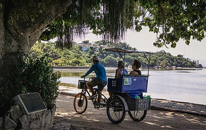 Triciclo transportando passageiros junto à orla arborizada da Ilha de Paquetá.
