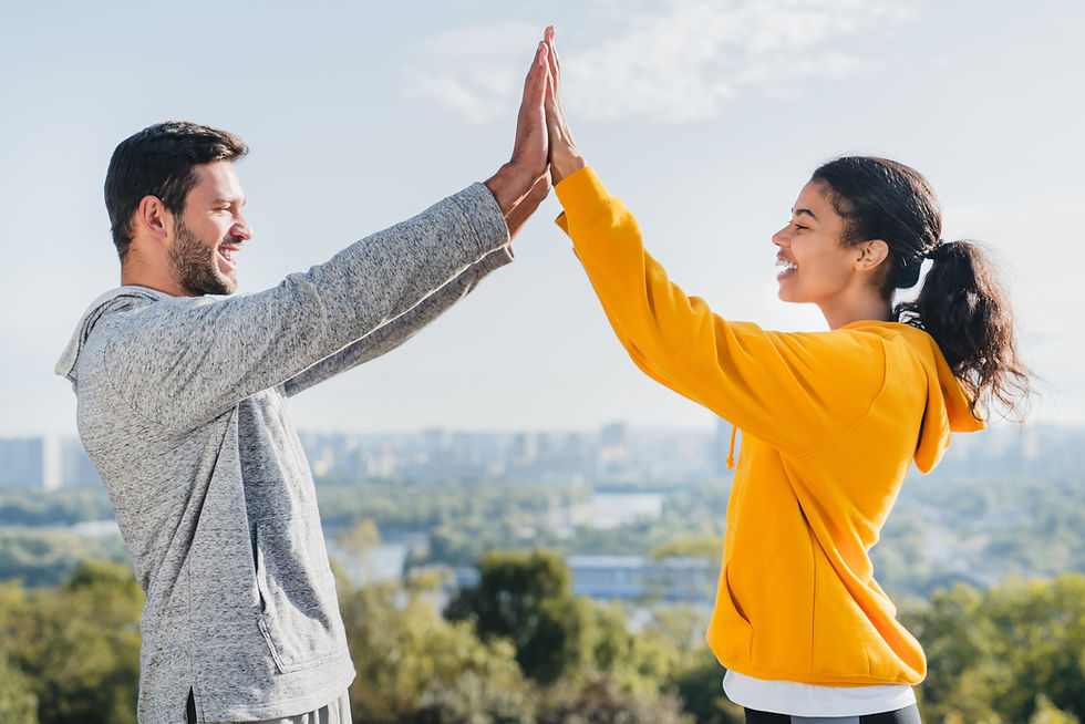 Young happy mixed race fit couple taking high five after successful training outside. Moti
