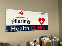 Indoor sign for Pilgrim's Health Clinic featuring bold typography and a heart symbol, designed by Mustang Signs and Graphics.