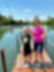Boy and woman fishing holding fish on wooden dock, blue water.