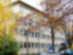 Modernes Englert Bürogebäude umgeben von bunten Herbstbäumen und parkenden Autos davor.