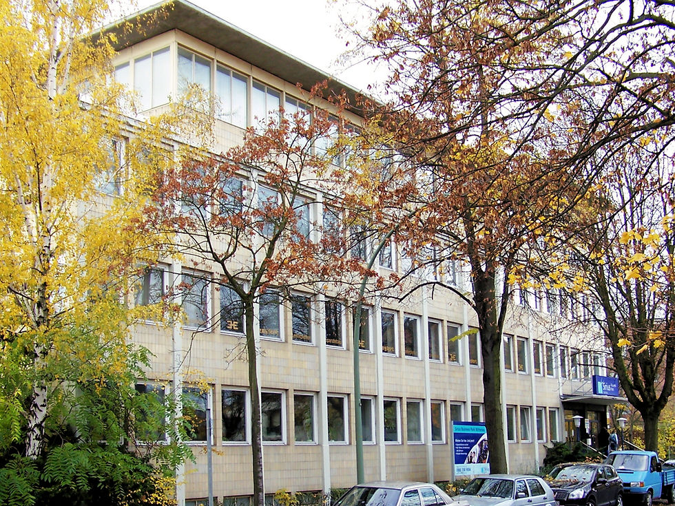 Modernes Englert Bürogebäude umgeben von bunten Herbstbäumen und parkenden Autos davor.
