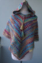 Rainbow Spell hooded crochet poncho for youth, handmade colorful poncho with tassel drawstring displayed on mannequin.