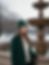 Woman wearing a handmade green crochet beanie near a fountain in a snowy park