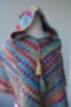 Rainbow Spell handmade crochet poncho for youth with hood and tassel ties in multicolor yarn.