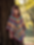 Child wearing Rainbow Spell hooded crochet poncho, colorful handmade youth poncho with tassel ties.