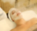 Person enjoying a relaxing facial mask treatment at Transcendence Spa, with steam and a serene atmosphere.