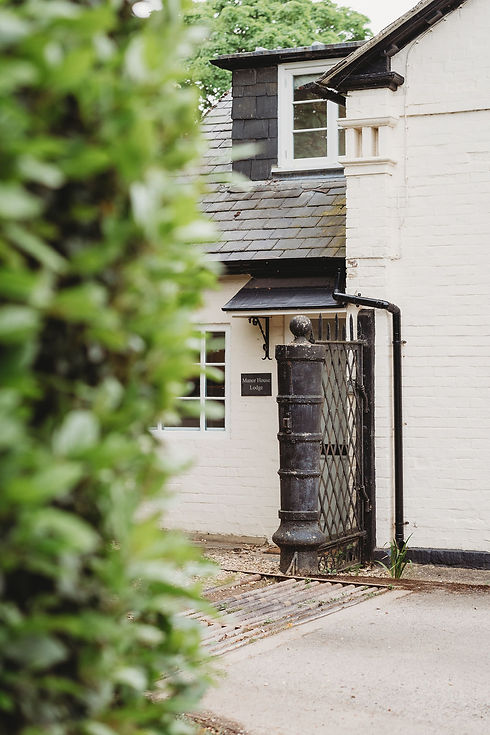 The entrance to manor House Lodge showing a cream cottage