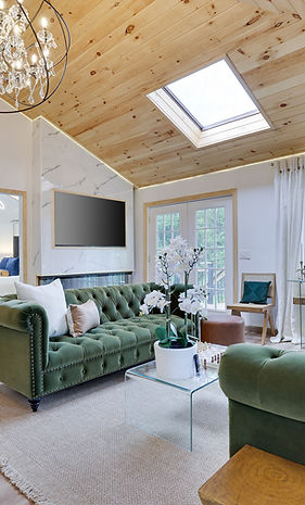 Luxury livingroom with smart TV, fireplacem sky light, tufted velvet sofas and lots of windows.
