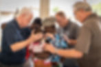 Elders and staff members praying over an African woman and her child.