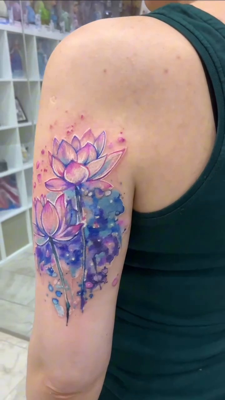 Resultado del cover-up de escorpión: flores de loto rosas y violetas con fondo de acuarela azul en el brazo