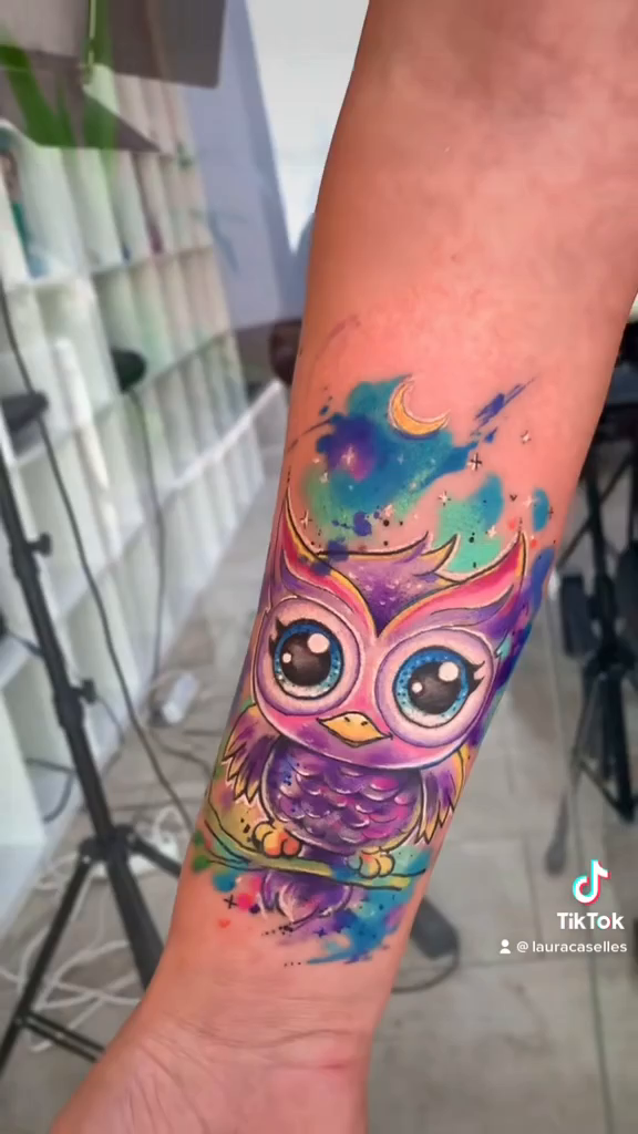 Cover-up de Laura Caselles: búho a color de ojos turquesa, cuerpo violeta y rosa, rama y luna en el antebrazo