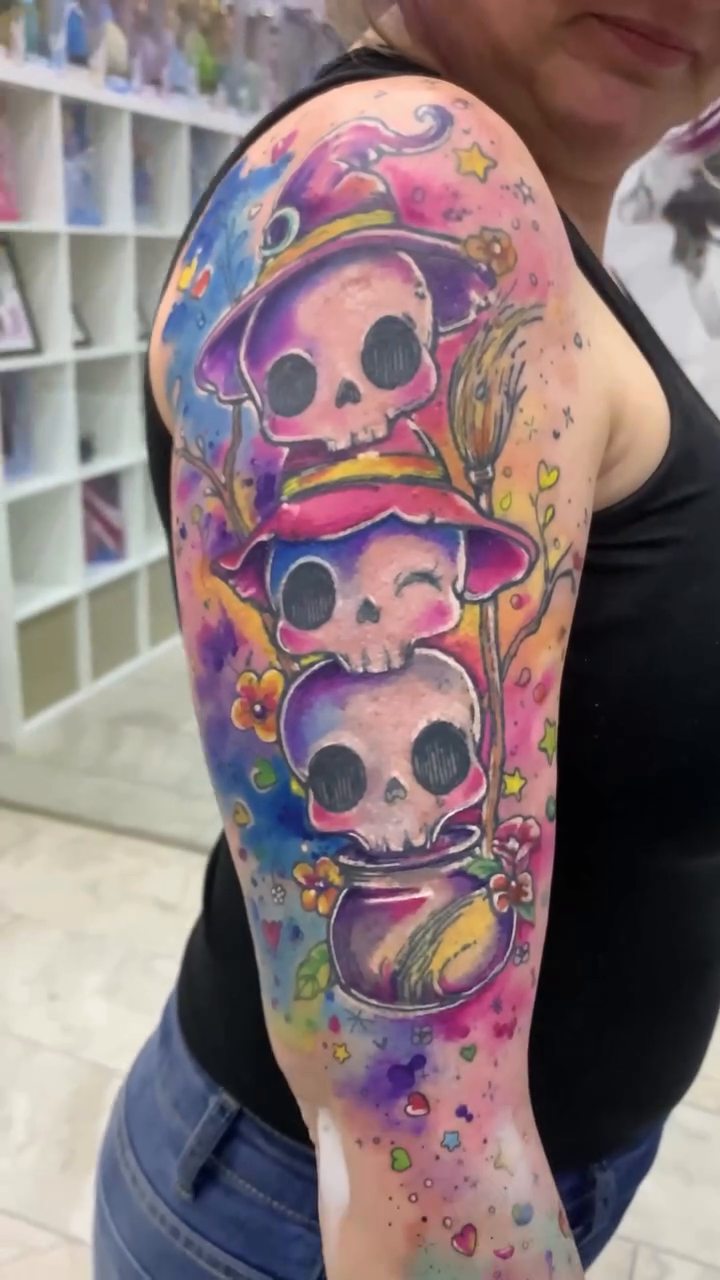 Calaveritas con sombreros, flores y acuarela rosa, violeta y azul en el brazo