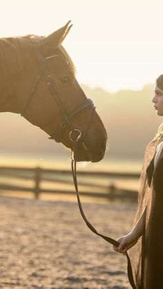 Lauren Elizabeth Pye in a sunlit photo of her in a back cape and her horse Manny
