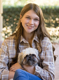 Lauren, smiles, in jeans, holding her dog