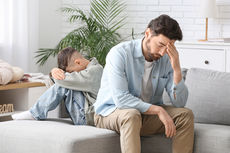 Father and son appearing frustrated while dealing with a child’s bedwetting or potty accidents.