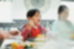 young asian boy eating food and smiling with family