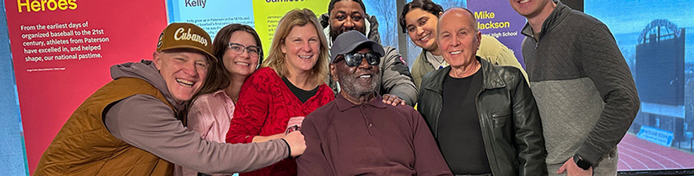 Group photo of diverse people with "Hometown Heroes" text on display.