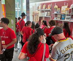 Group of people wearing red shirts exploring exhibits with visible text.