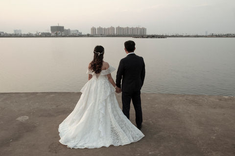 A couple stares at the artificial lake within the That Luang Lake SEZ during their wedding shooting. Vientiane Capital, Laos. February 2022.