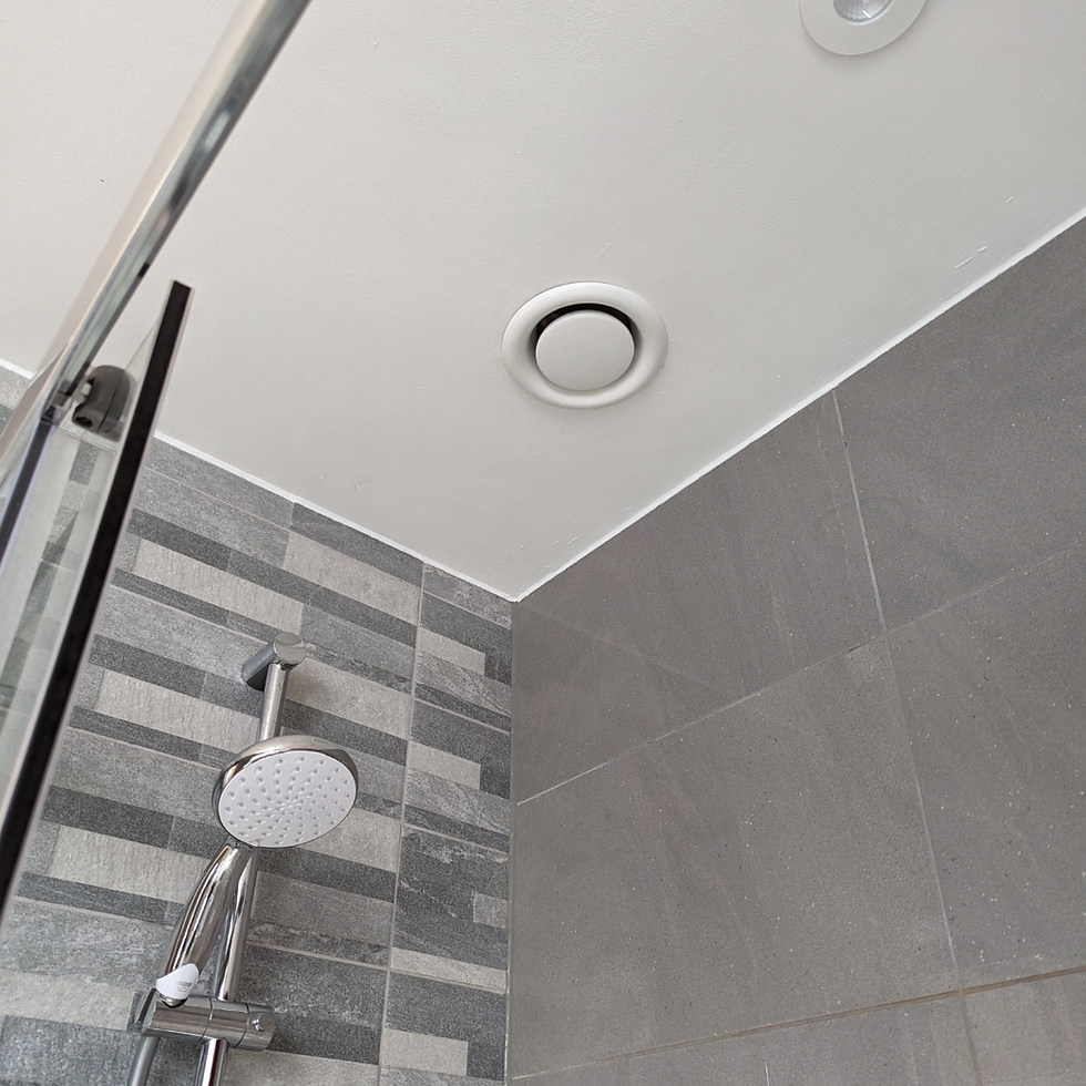 Modern gray-tiled shower stall with chrome showerhead and ceiling vent, viewed upward in a clean bathroom.
