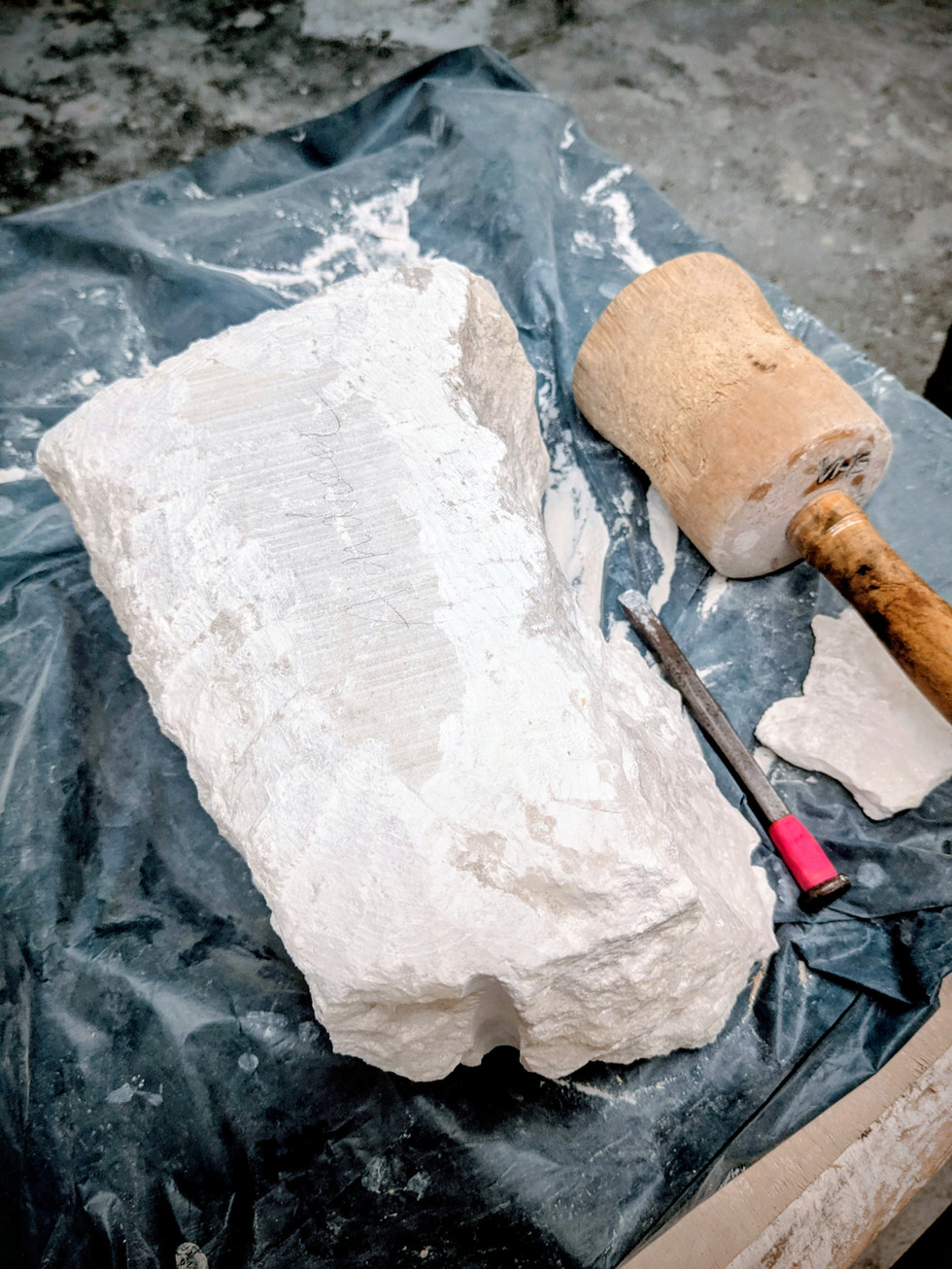 Block Alabaster unbearbeitet auf einer Arbeitsfläche mit Werkzeug daneben.