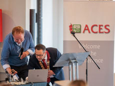 Harry Bunbury and ACES President Alan Richards leaning over a laptop at the presentation lectern during the ACES National Conference.