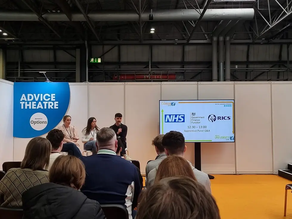 A live audience watching a three-person apprentice panel discussion at an event stage labeled "Advice Theatre."