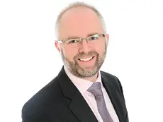 Professional headshot of Chris Plumley, Public Sector Real Estate Partner at Trowers & Hamlins, wearing a suit and glasses.