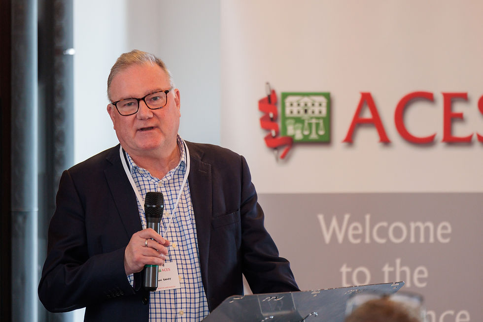 Simon Bandy speaking into a handheld microphone at the podium about Local Government Reorganisation.