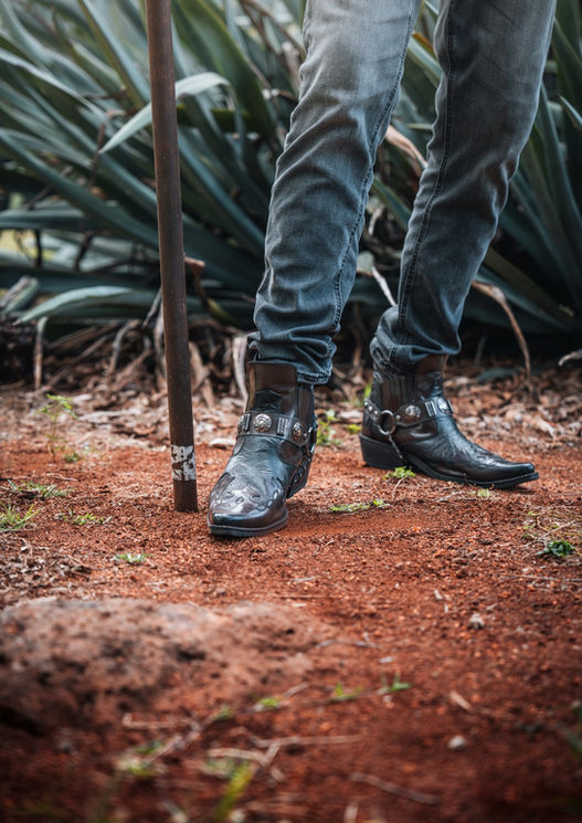 Boots on red soil beside a steel pole, with agave leaves behind